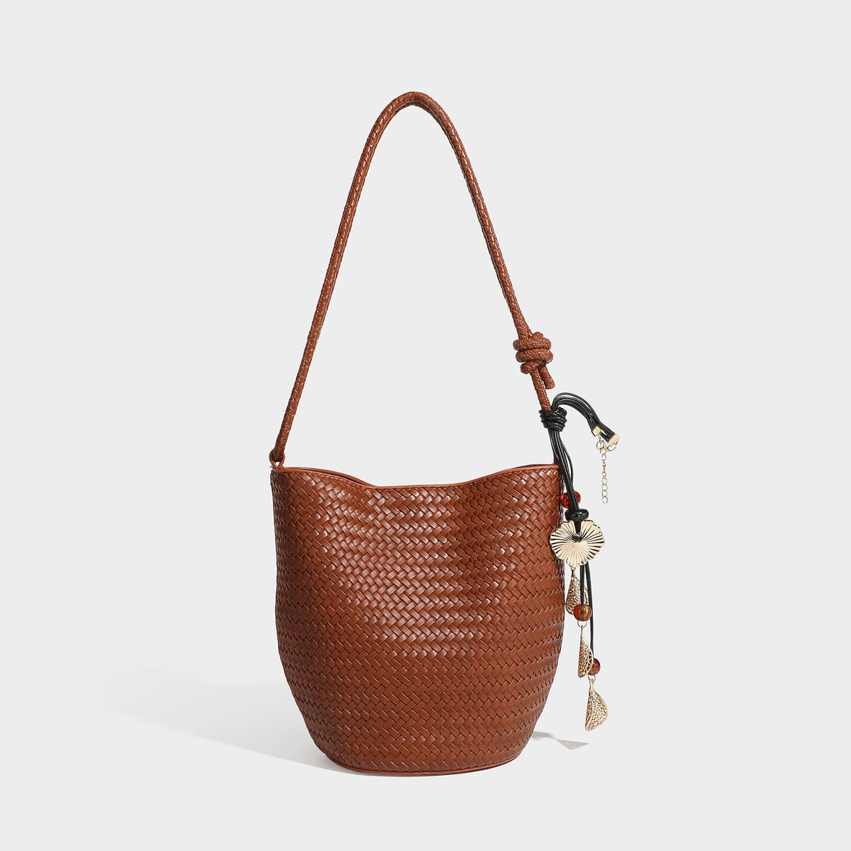 Olive green woven leather-look bucket bag with braided crossbody strap, knotted adjustment, and gold-tone tassel charm with