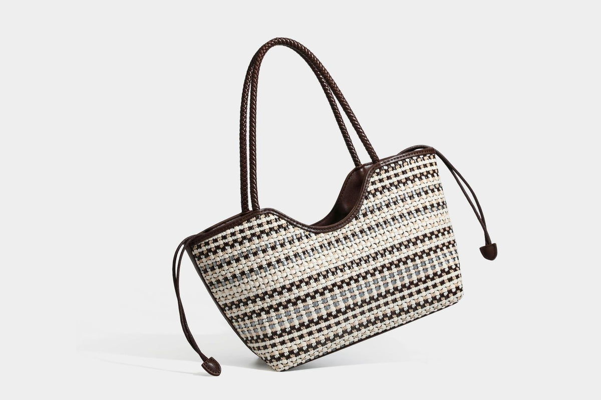 Large woven checker-pattern tote bag with dark braided shoulder straps, leather-look trim, and drawstring side ties, detail
