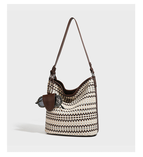 Woven stripe bucket shoulder bag in cream and dark brown with leather-look trim, knotted adjustable strap, and small shield
