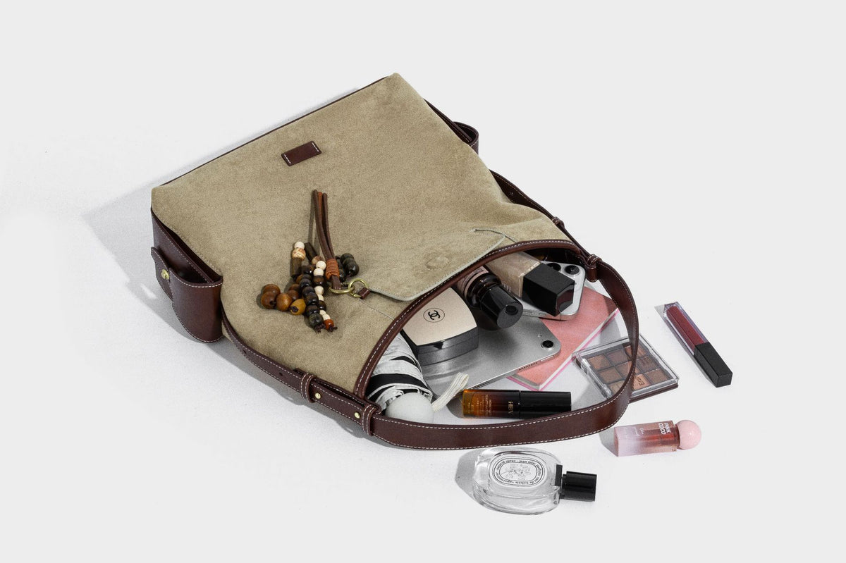 Lässig fallende Hobo-Schultertasche in Khaki aus mattem Material in Wildlederoptik mit dunkelbraunem Besatz in Lederoptik, Quastenanhänger mit Perlen und seitlicher Klappe, Detailansicht
