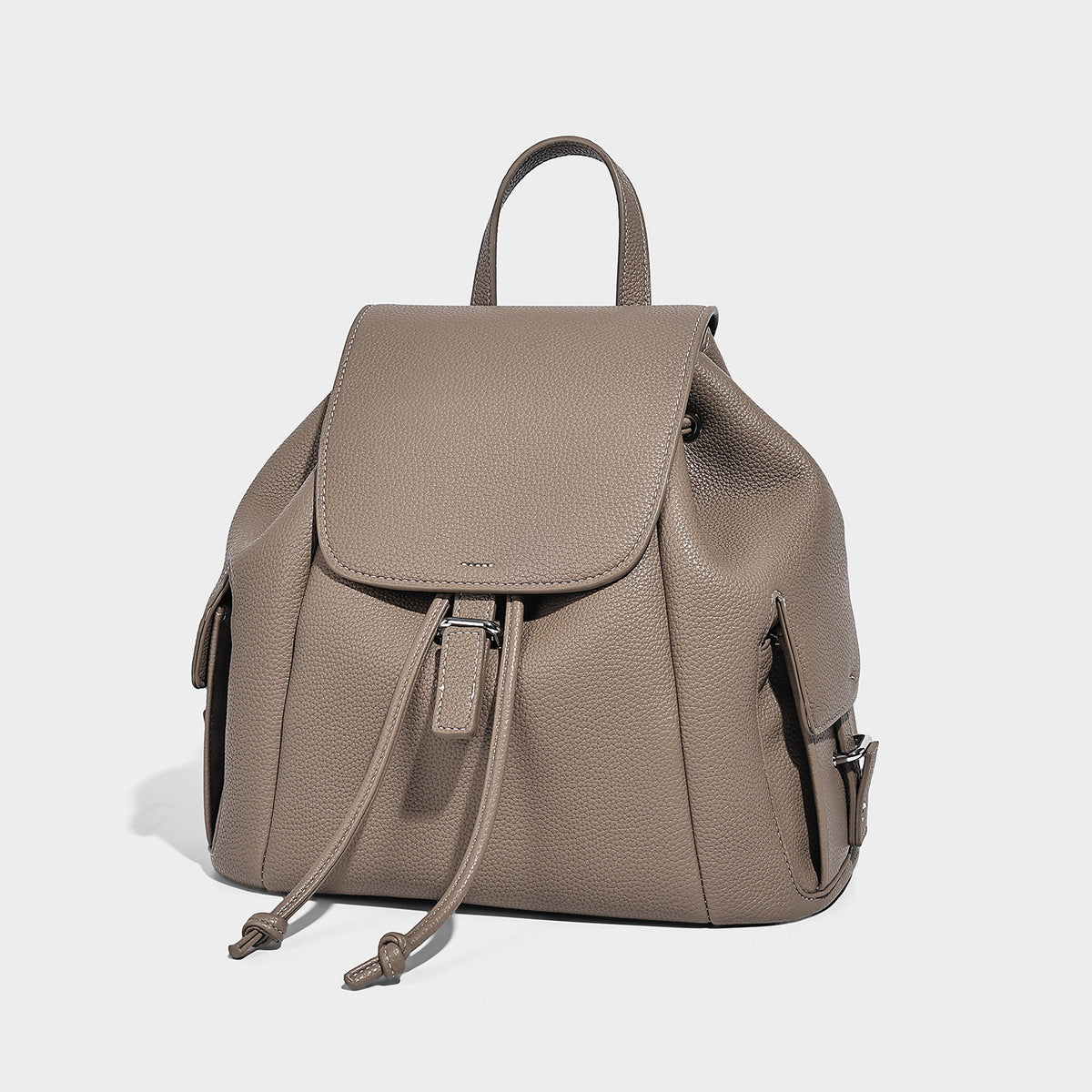 Compact pebbled leather-look flap drawstring backpack handbag with side pockets, top handle, and silver-tone hardware, detail