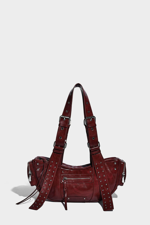 Glossy black crescent shoulder bag with silver-tone rivets, multiple zip pockets, and long adjustable studded straps, detail