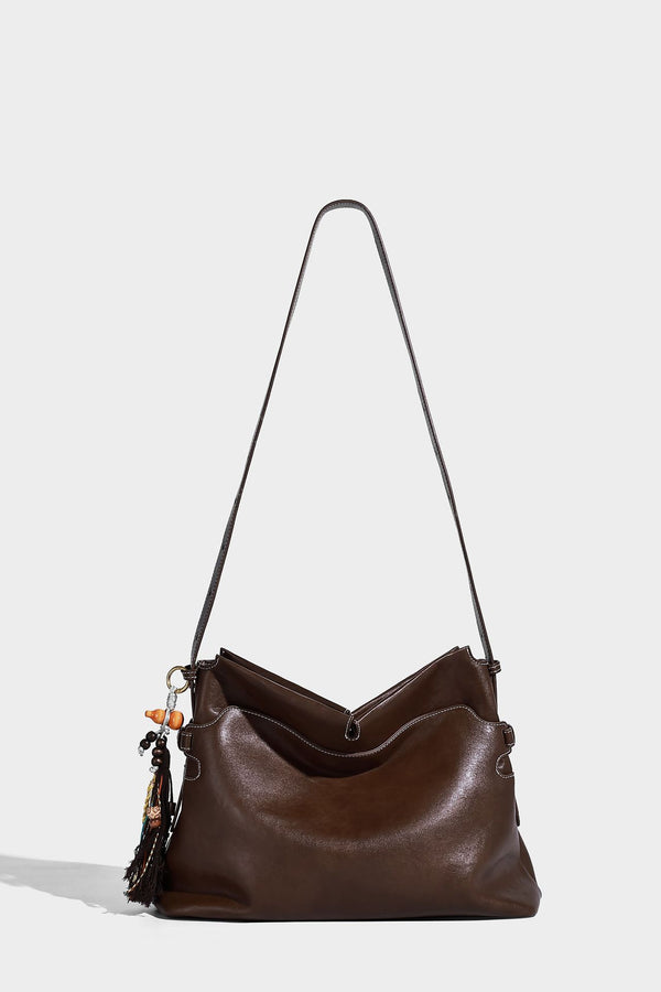 Large slouchy leather-look hobo tote bag with open top, adjustable shoulder strap, and colorful tassel bead charm, detail