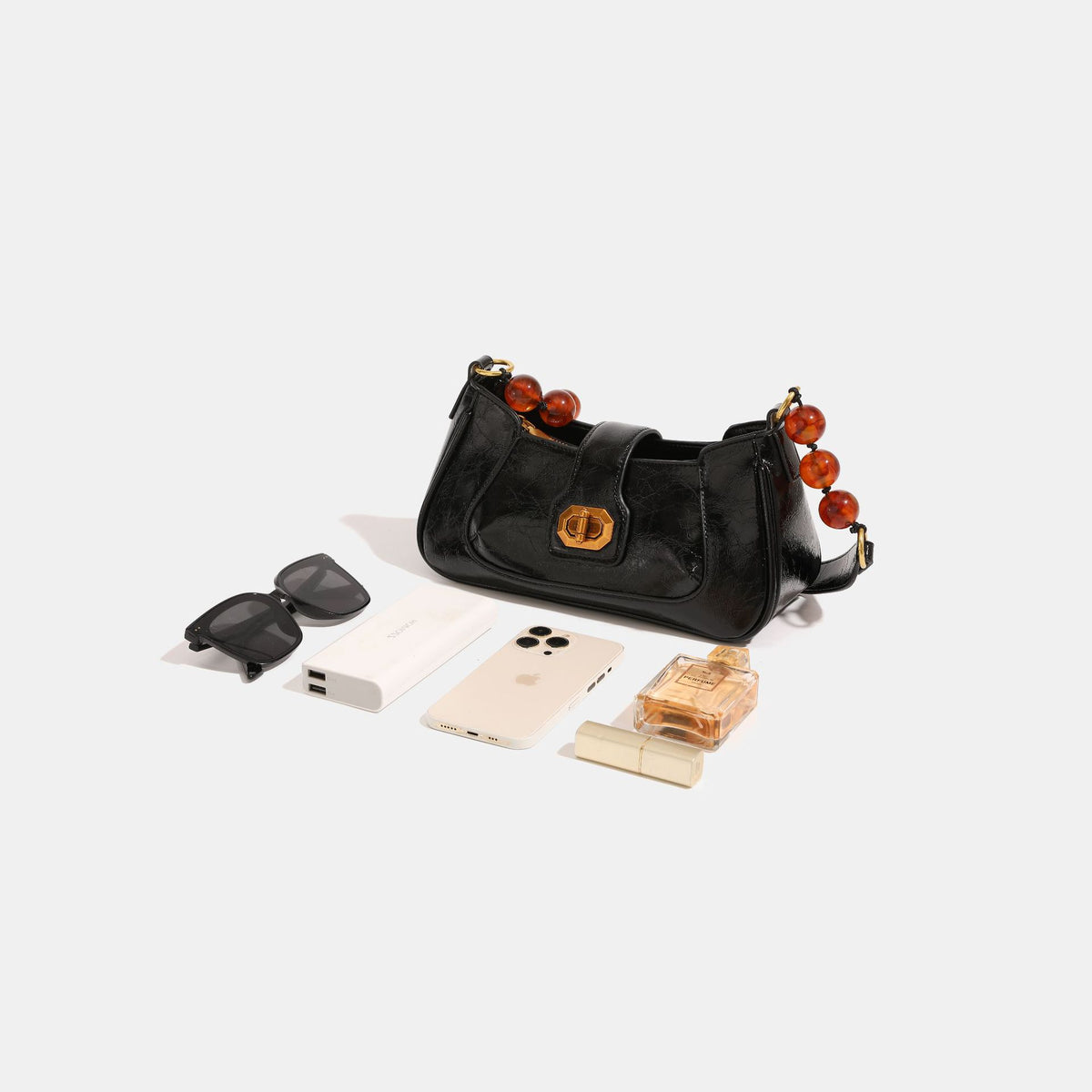 Compact glossy crinkled baguette shoulder bag with amber resin bead strap accent and gold-tone turn-lock closure, detail view