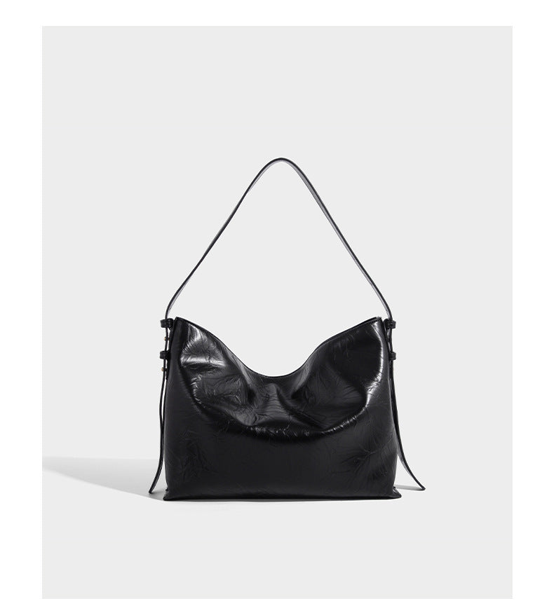 Large slouchy hobo shoulder bag in glossy crinkle leather-look finish with gold-tone emblem hardware and adjustable strap