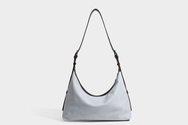 Slouchy olive green canvas hobo shoulder bag with black leather-look trim, zip-top closure, and adjustable strap, detail view