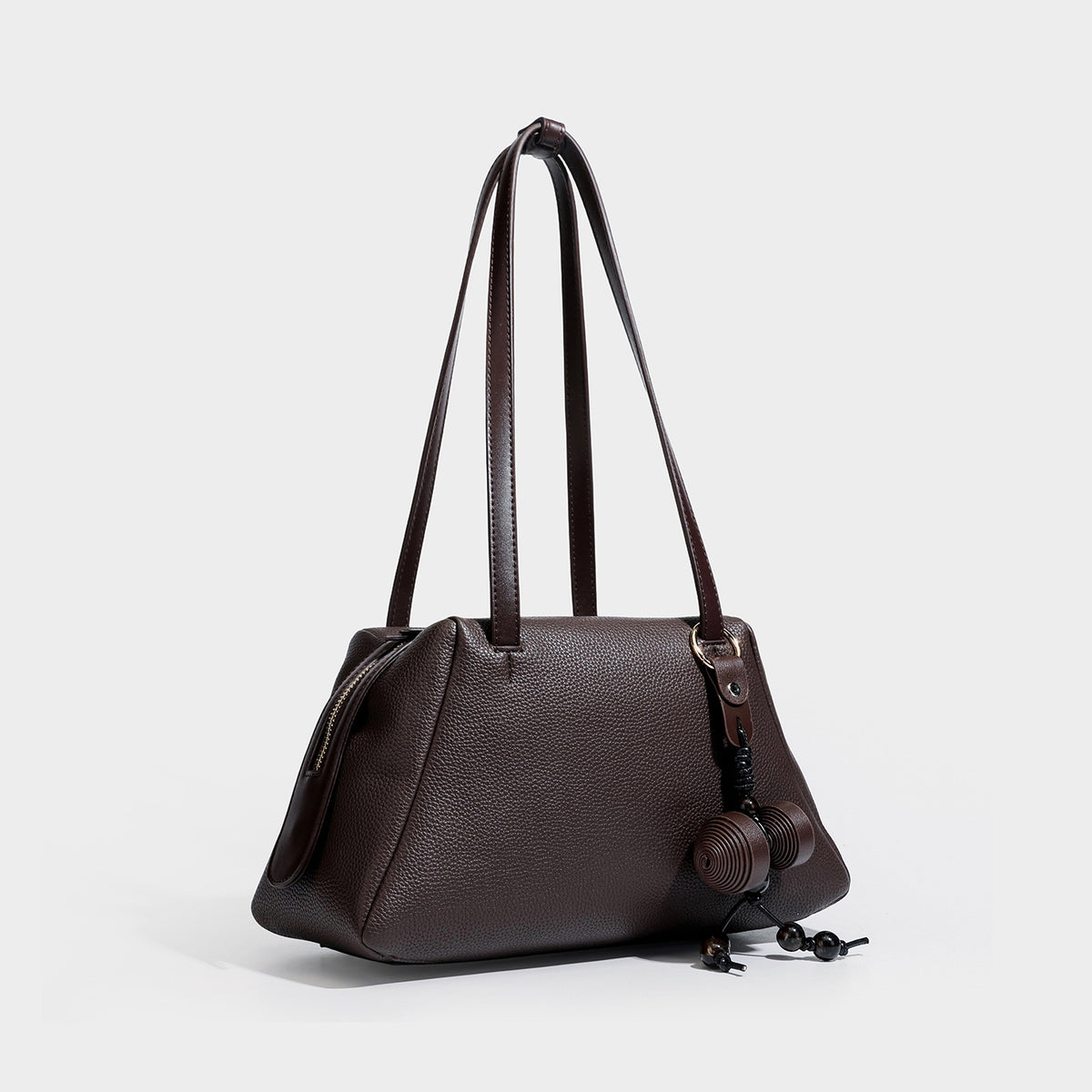 Structured trapezoid shoulder bag in dark brown pebbled leather-look finish with slim double straps, top zip closure, side