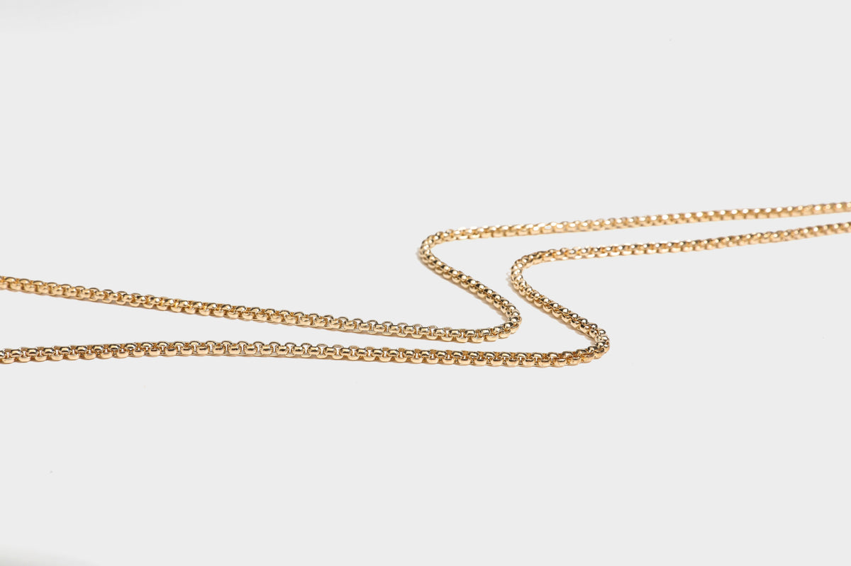 Small structured metallic woven-texture box clutch bag with jeweled kiss-lock dome clasp and slim gold chain strap, detail