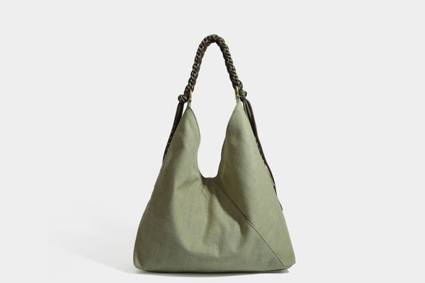 Soft slouchy cream canvas shoulder tote with braided brown and green cord handle, gold-tone ring hardware, and tassel trim