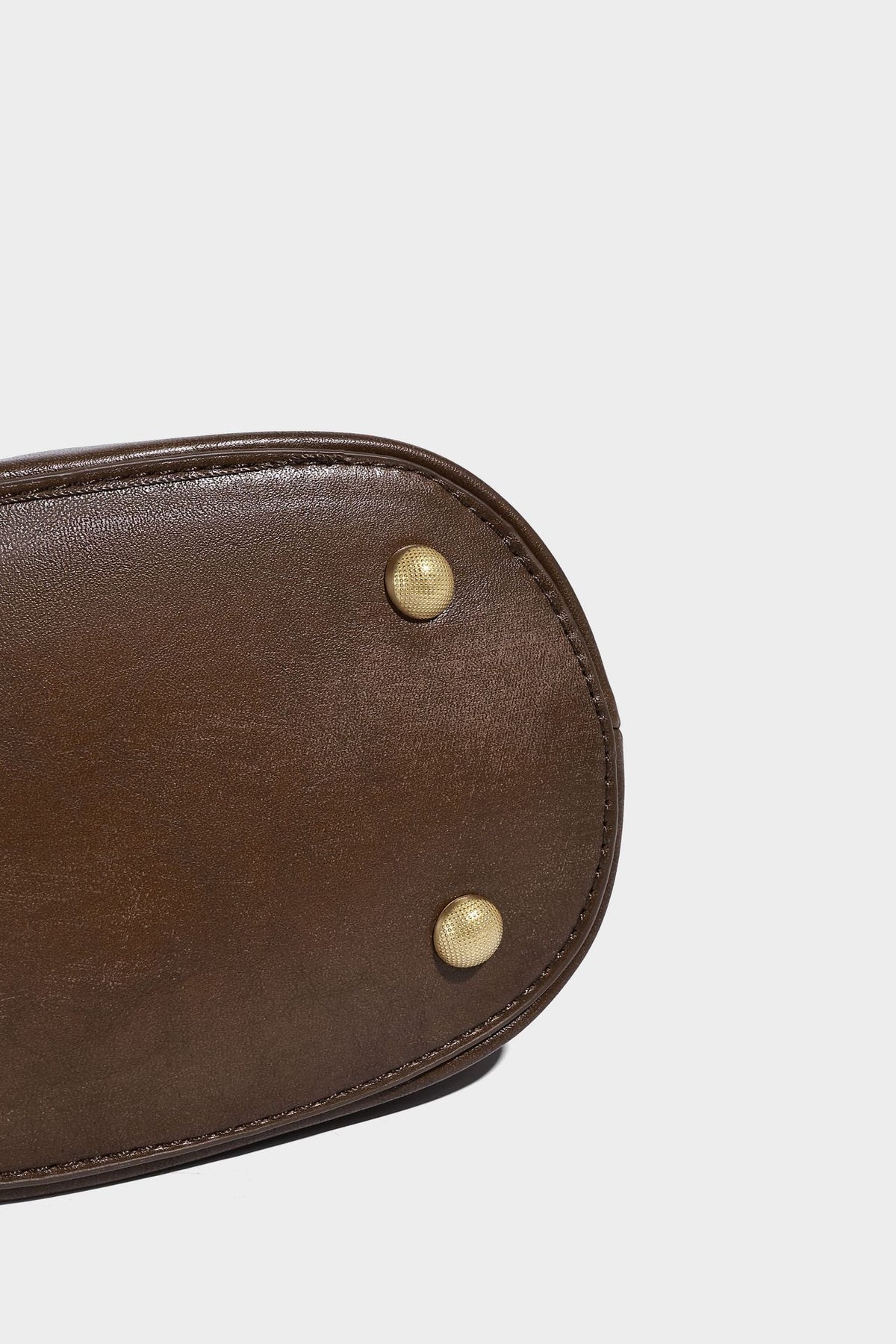 Small woven-panel bucket bag with circular ring handles, beaded tassel charm, and detachable crossbody strap in brown, detail