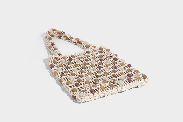 Cream macramé open-weave tote bag with multicolor amber olive and translucent bead accents and woven shoulder straps, detail