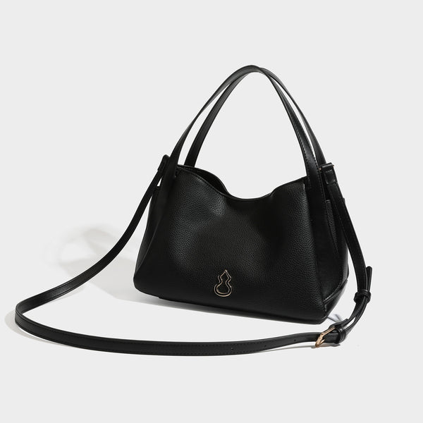 Schwarze Tote-Tasche in genarbter Lederoptik mit goldfarbenen, kürbisförmigen Beschlägen, zwei Tragegriffen und abnehmbarem Crossbody-Riemen, Detailansicht
