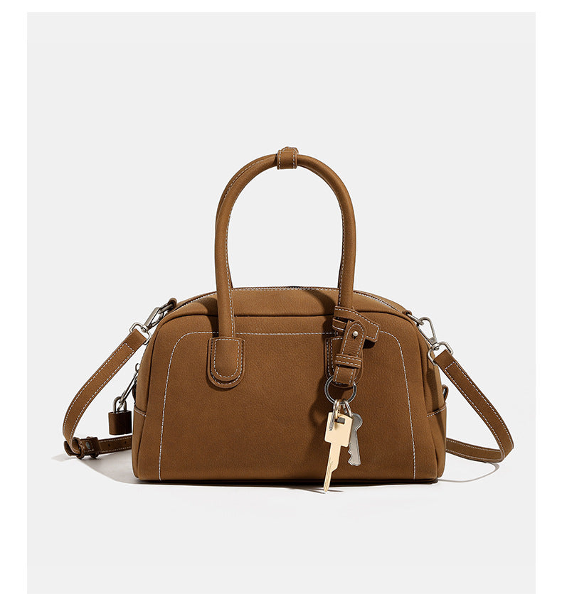 Kompakte, strukturierte Henkeltasche mit matter genarbter Oberfläche, geknoteten Doppelhenkeln, goldenem Schlüsselanhänger und abnehmbarem, Detail