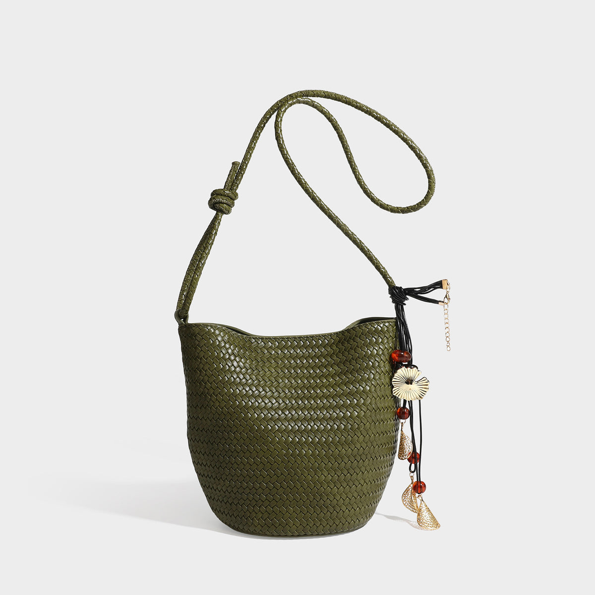 Olive green woven leather-look bucket bag with braided crossbody strap, knotted adjustment, and gold-tone tassel charm with
