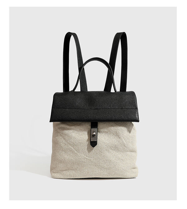 Strukturierter beigefarbener Rucksack aus gewebtem Canvas mit schwarzer Klappe in Lederoptik, Drehverschluss, Tragegriff und flachem Schulter