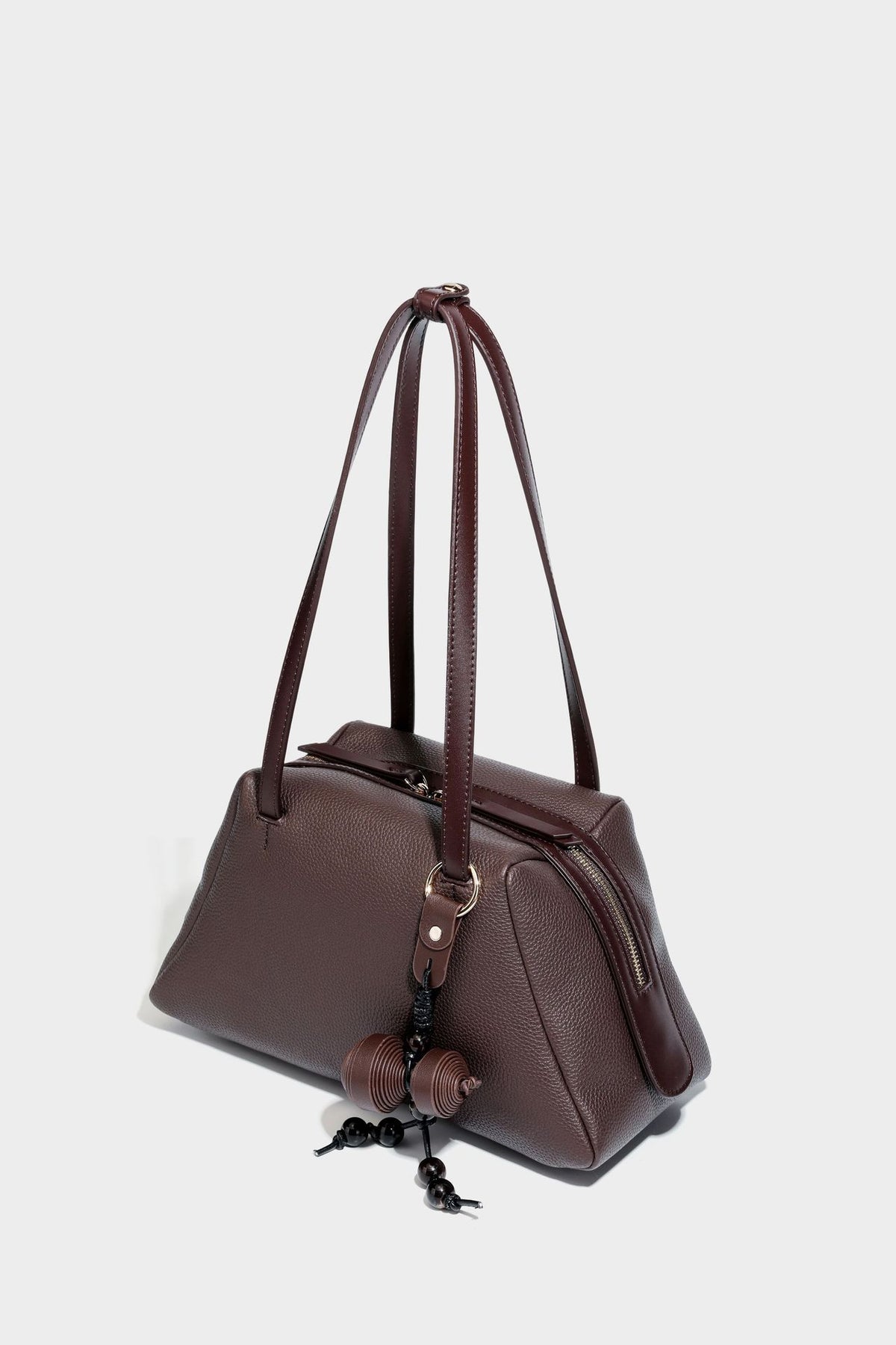 Structured trapezoid shoulder bag in dark brown pebbled leather-look finish with slim double straps, top zip closure, side