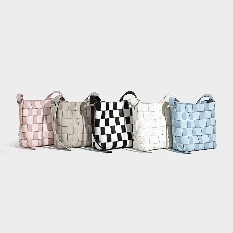 Hand-woven black-and-white checkerboard bucket bag with smooth black trim, silver-tone ring hardware, and adjustable