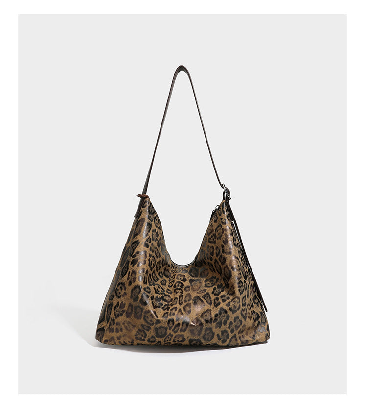 Slouchy leopard print hobo shoulder bag with glossy coated finish, top zipper closure, dark brown trim, and dangling charm