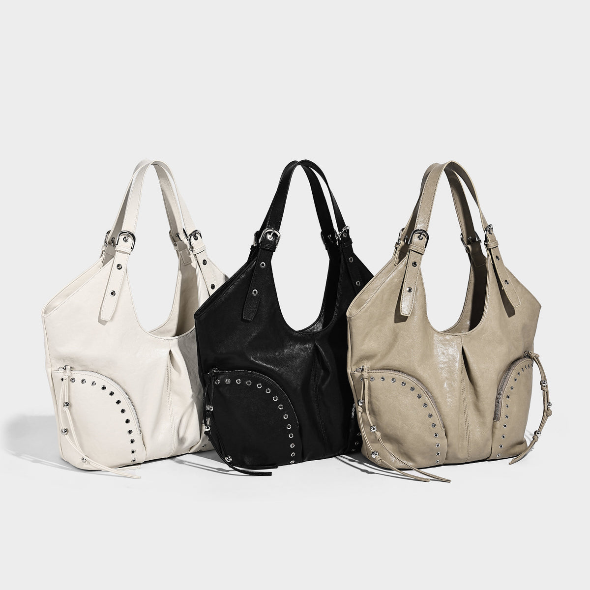 Large slouchy leather-look hobo shoulder bag with silver rivets, grommet-trimmed front zip pockets, and adjustable dual