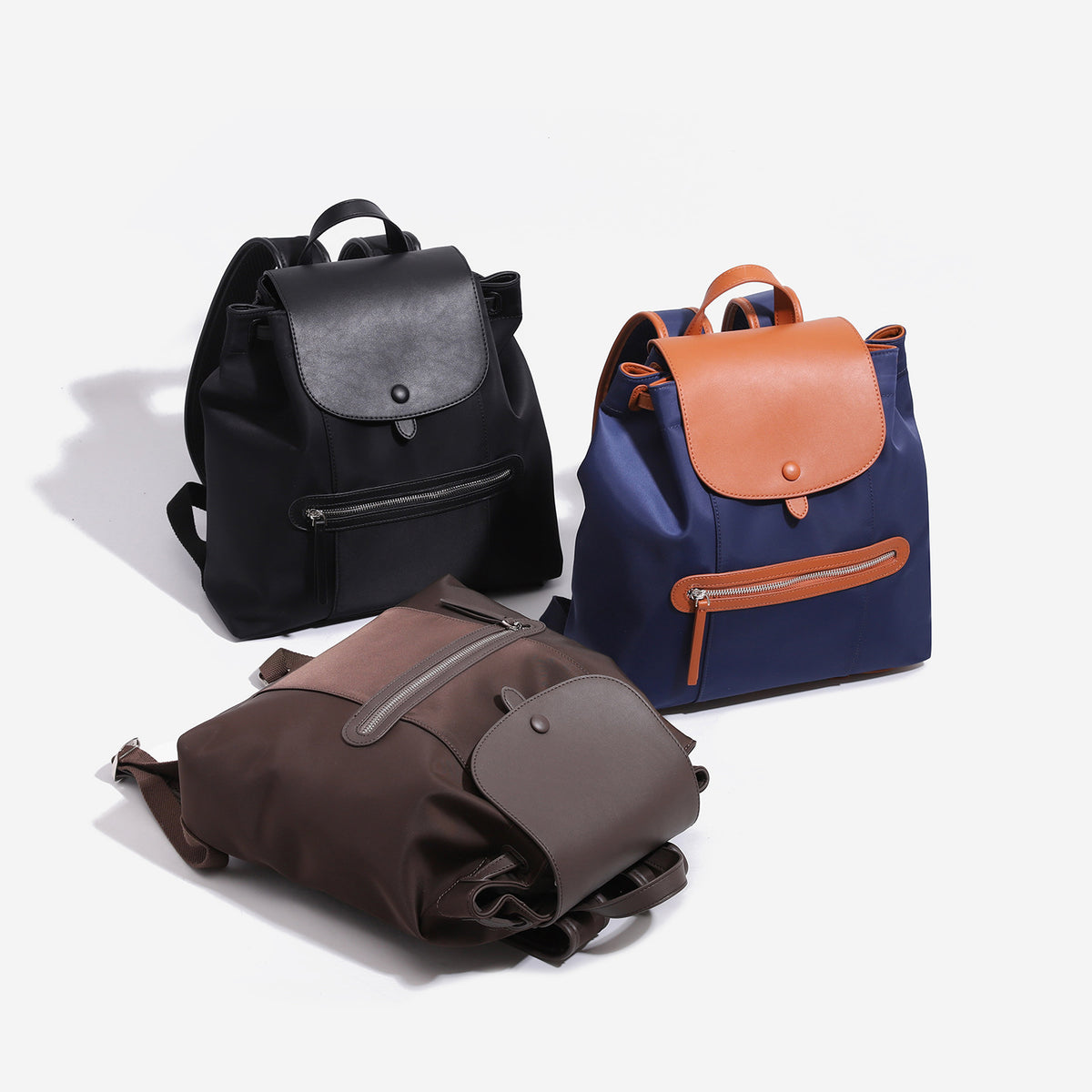 Large flap-top nylon backpack with leather-look trim, snap closure, front zip pocket, and padded shoulder straps, front view