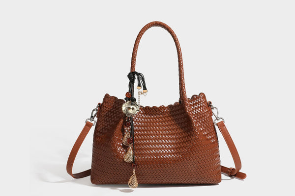 Strukturierter, glänzend geflochtener Shopper mit Muschelkantenabschluss am oberen Rand, geflochtenen Tragegriffen, abnehmbarem Crossbody-Riemen und Perlenquaste