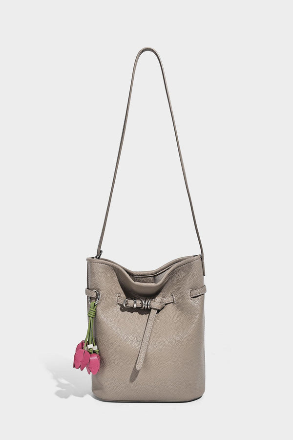 Small pebbled leather-look bucket bag with front drawstring toggle hardware and long adjustable shoulder strap, detail view