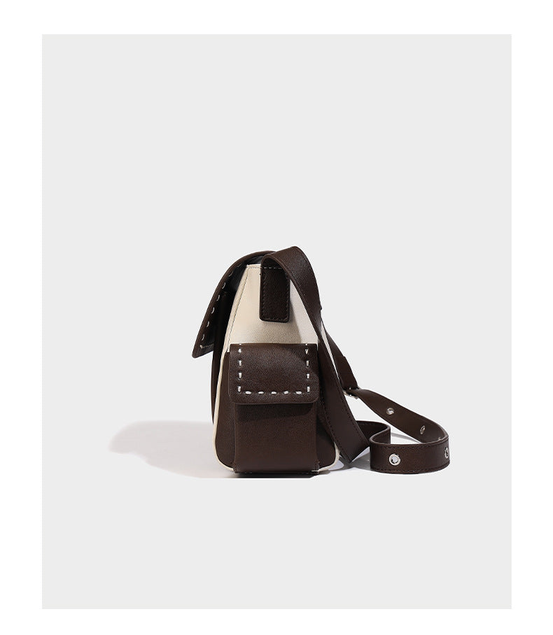 Structured flap crossbody bag in dark brown and cream color-block with white contrast stitching, adjustable shoulder strap