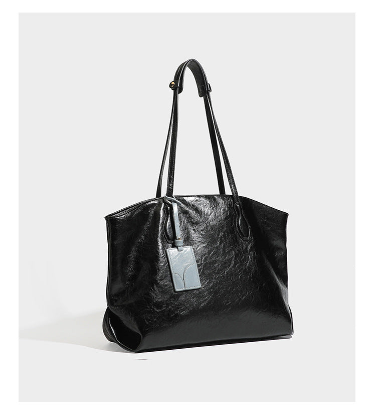 Übergroße, weich fallende Tote-Bag in dunklem Bordeauxrot mit glänzender, geknautschter Lederoptik, zwei langen Schulterriemen und Kontrast