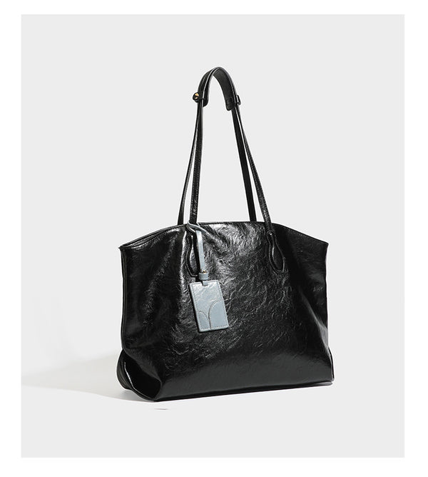 Übergroße, weich fallende Tote-Bag in dunklem Bordeauxrot mit glänzender, geknautschter Lederoptik, zwei langen Schulterriemen und Kontrast