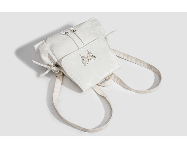 Compact white pearlescent flap backpack with silver-tone bow hardware and drawstring closure, detail view 7
