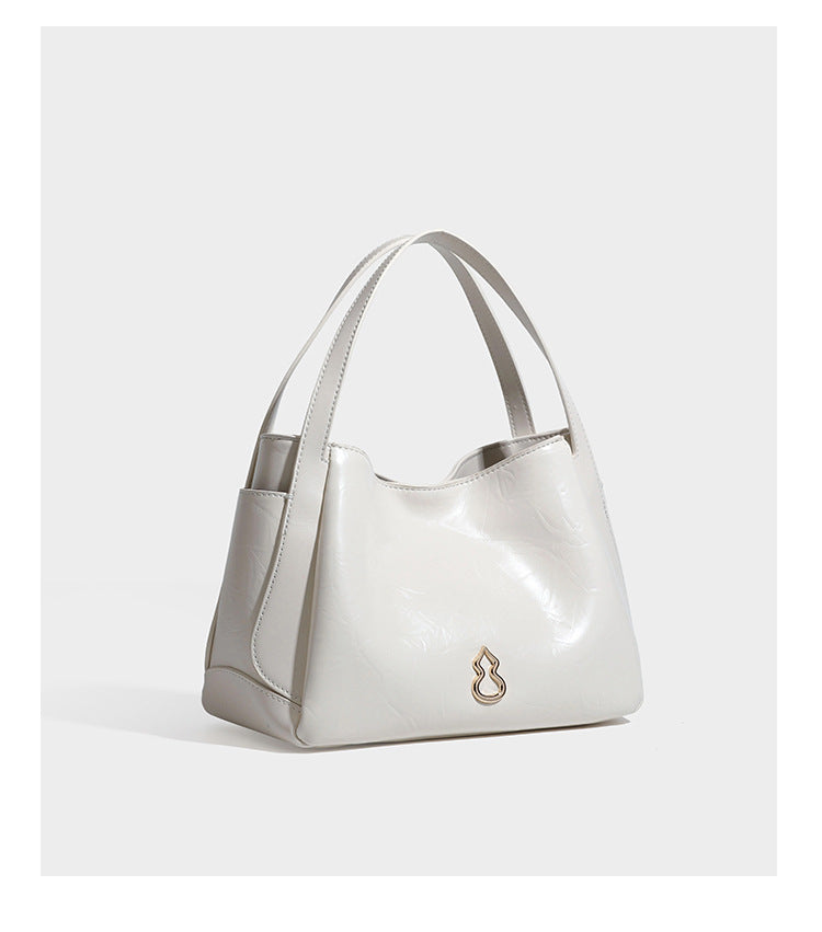 Black glossy crinkled leather-look convertible shoulder tote bag with gold gourd-shaped emblem hardware and detachable