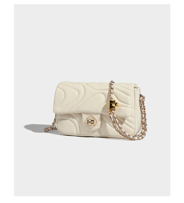 Compact cream quilted flap crossbody bag with wave stitching, gold-tone chain strap, and four-petal turn-lock clasp, detail