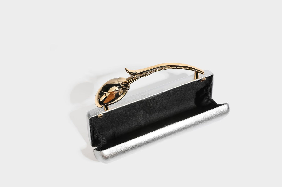 Strukturierte rechteckige Clutch mit goldfarbenem Henkel in Form einer Rosenknospe und abnehmbarem Kettenriemen in Metallic-Optik, Detailansicht