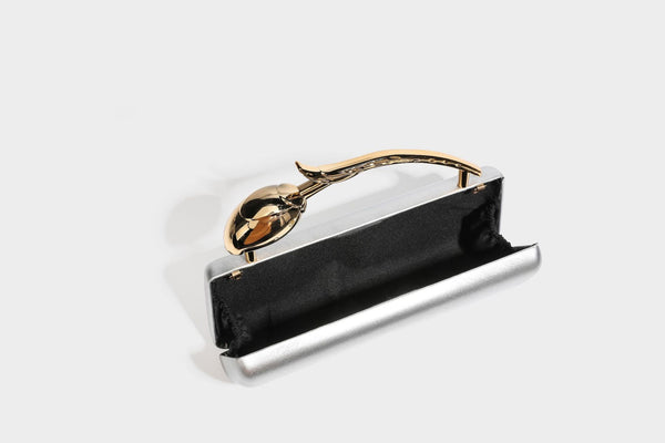 Strukturierte rechteckige Clutch mit goldfarbenem Henkel in Form einer Rosenknospe und abnehmbarem Kettenriemen in Metallic-Optik, Detailansicht