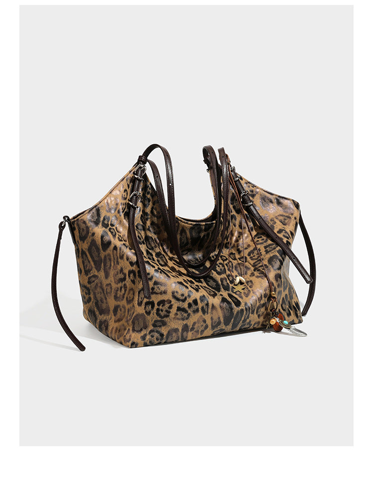 Slouchy leopard-print shoulder tote bag in tan and brown with long double straps, side tie straps, and dangling charm, detail