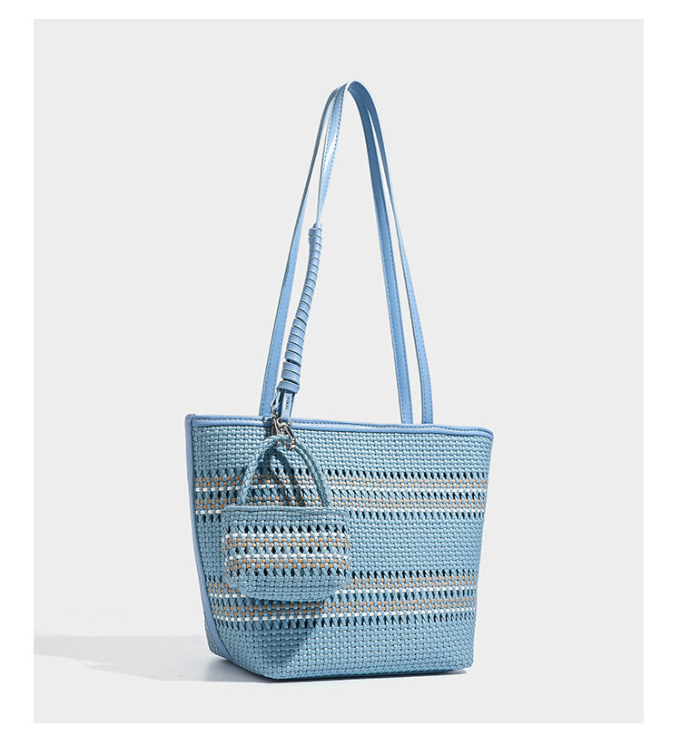 Large structured woven tote bag with striped basket-weave finish, long shoulder straps, and detachable mini pouch charm