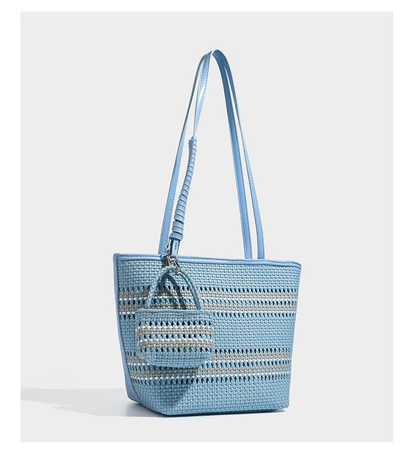 Large structured woven tote bag with striped basket-weave finish, long shoulder straps, and detachable mini pouch charm
