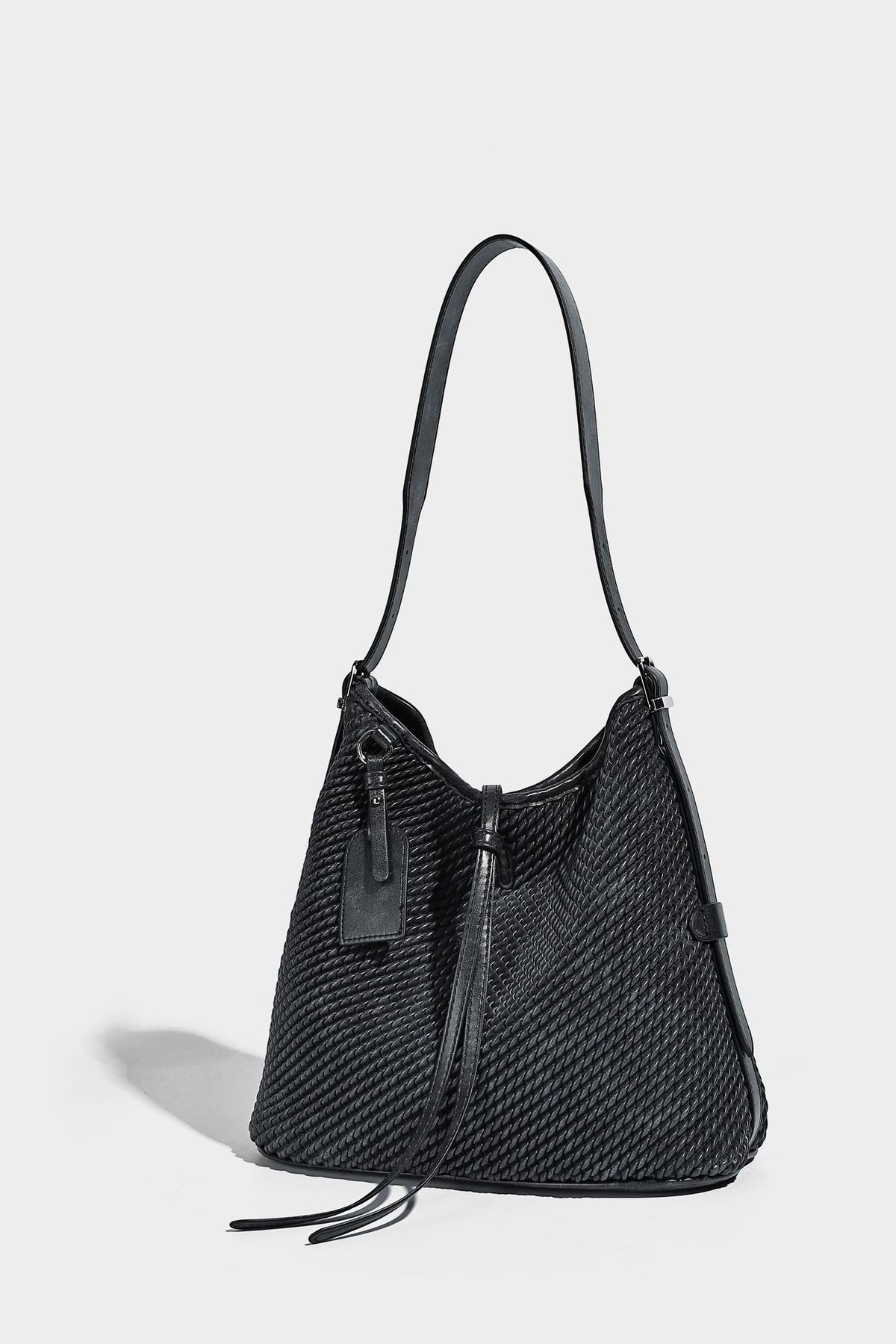 Große Schultertasche in Beutelform mit Flechtoptik, glatten Besätzen in Lederoptik, verstellbarem Riemen und hängendem Anhänger-Detail, Detailansicht