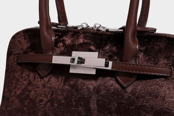 Small structured satchel bag in dark brown velvet-like textured finish with leather-look trim, silver-tone turn-lock bar