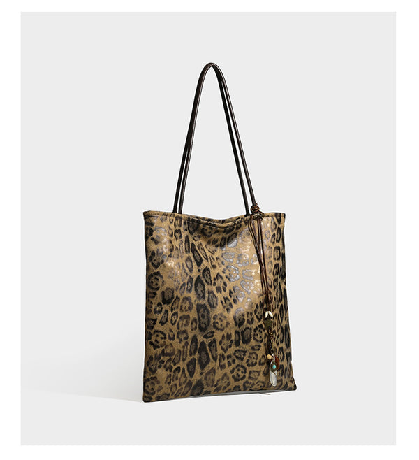 Large leopard print shoulder tote bag in tan and brown with slim dark straps and dangling beaded charm hardware, detail view