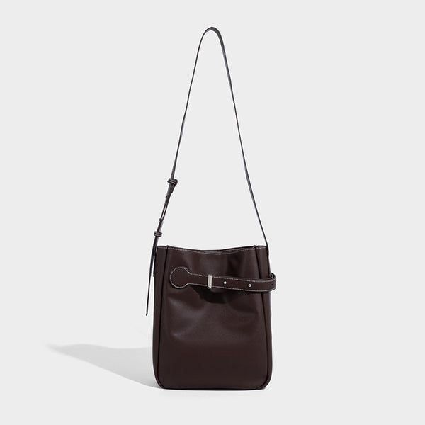 Structured dark brown leather-look bucket bag with white contrast stitching, front wraparound belt buckle strap, and long