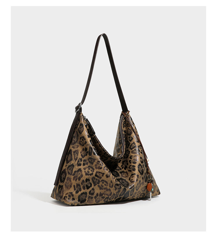 Slouchy leopard print hobo shoulder bag with glossy coated finish, top zipper closure, dark brown trim, and dangling charm