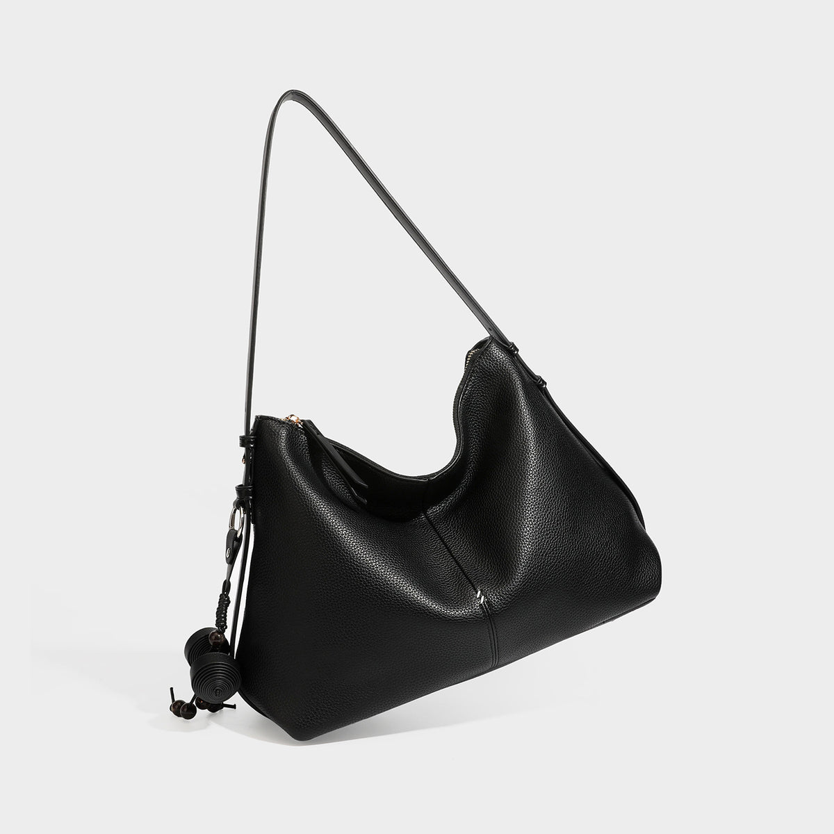 Slouchy hobo shoulder bag with pebbled leather-look finish, zip-top closure, gold-tone hardware, and hanging bead charm