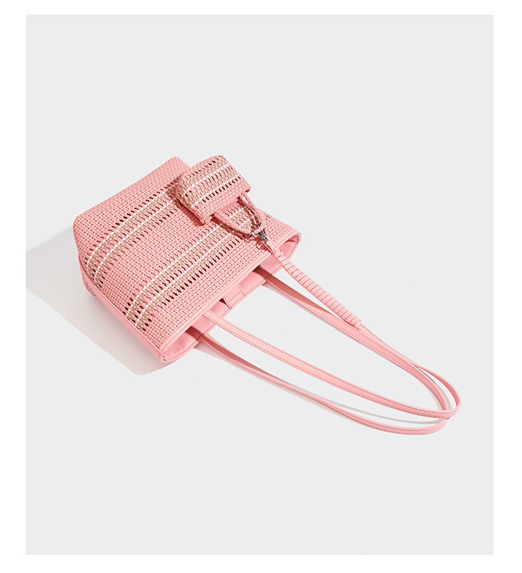 Large structured woven tote bag with striped basket-weave finish, long shoulder straps, and detachable mini pouch charm