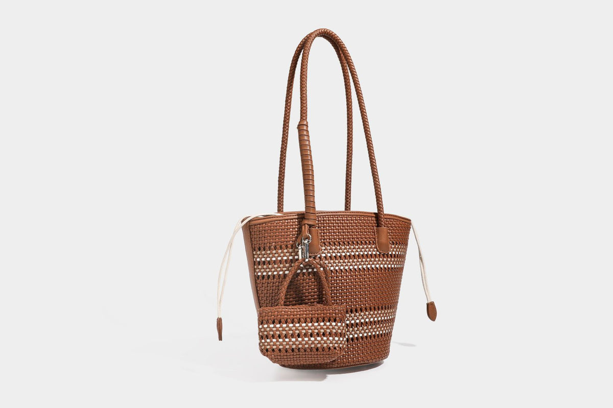 Light blue open-weave woven bucket tote bag with long braided shoulder straps, drawstring side ties, and attached mini pouch