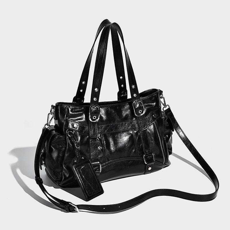 Glossy structured black tote shoulder bag with silver buckle hardware, zip pockets, dual top handles, and detachable, front