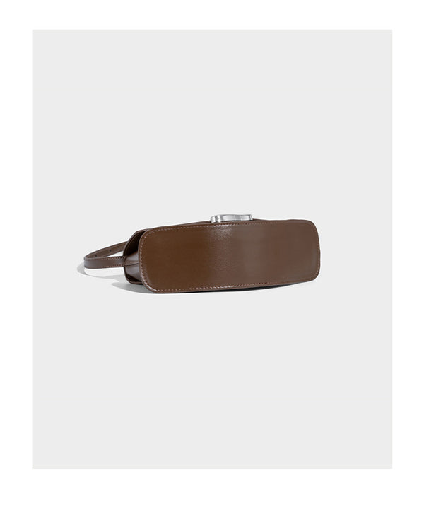 Small structured saddle bag with glossy leather-look finish, angular flap front, silver-tone metal clasp, and slim