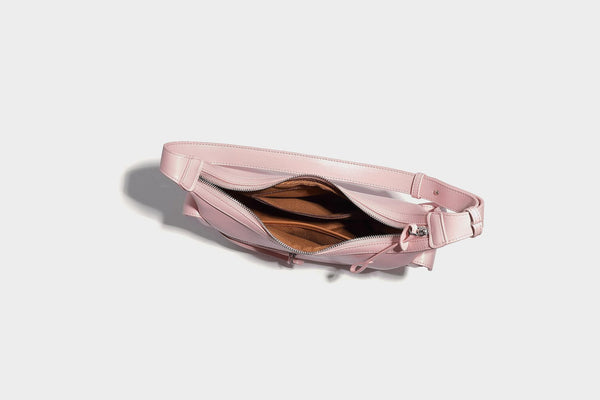 Smooth leather-look crescent shoulder bag with front zip pocket, side flap pockets, adjustable strap, and silver-tone, detail