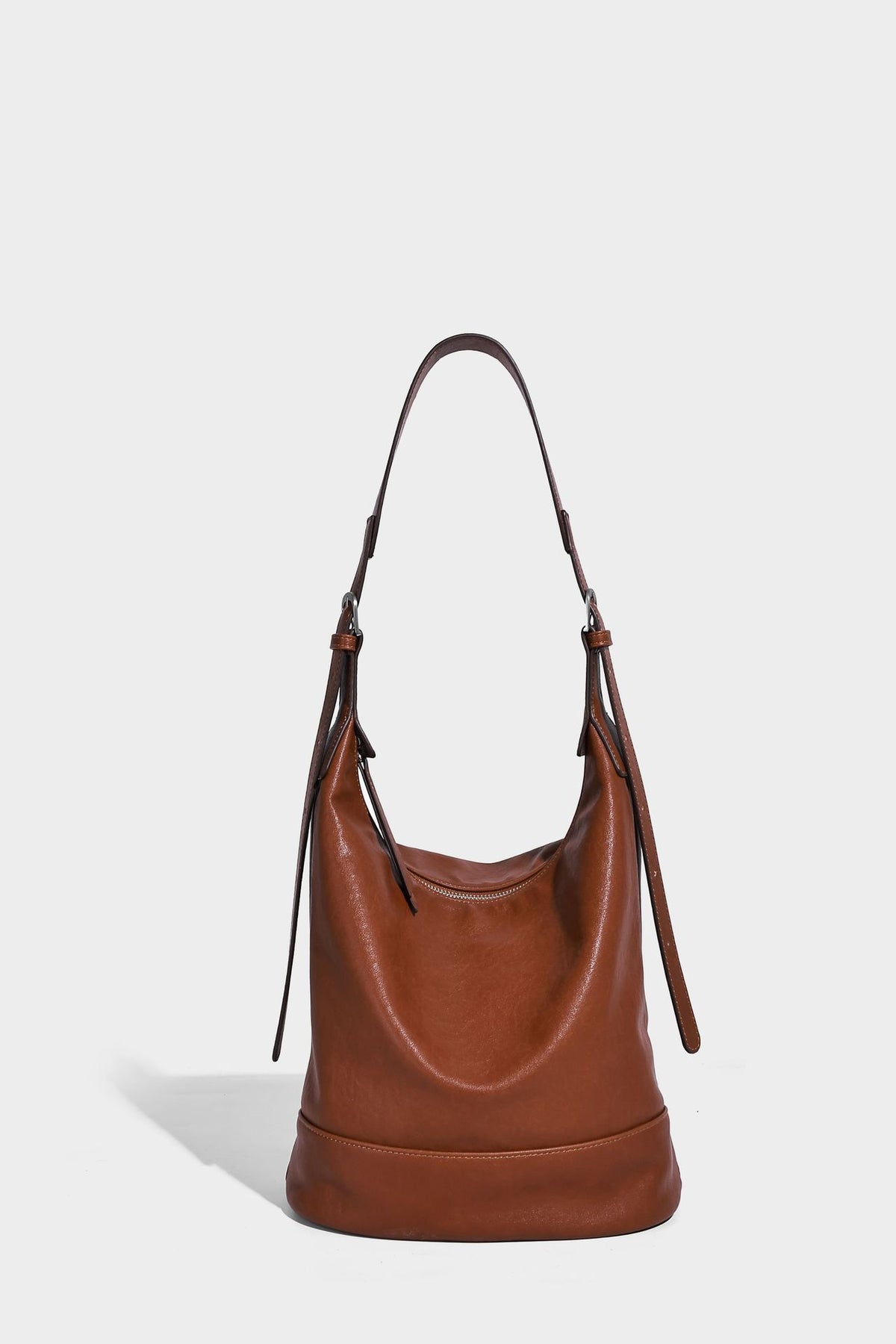 Slouchy bucket hobo shoulder bag in dark brown with glossy leather-look finish, top zip closure, and long adjustable, detail