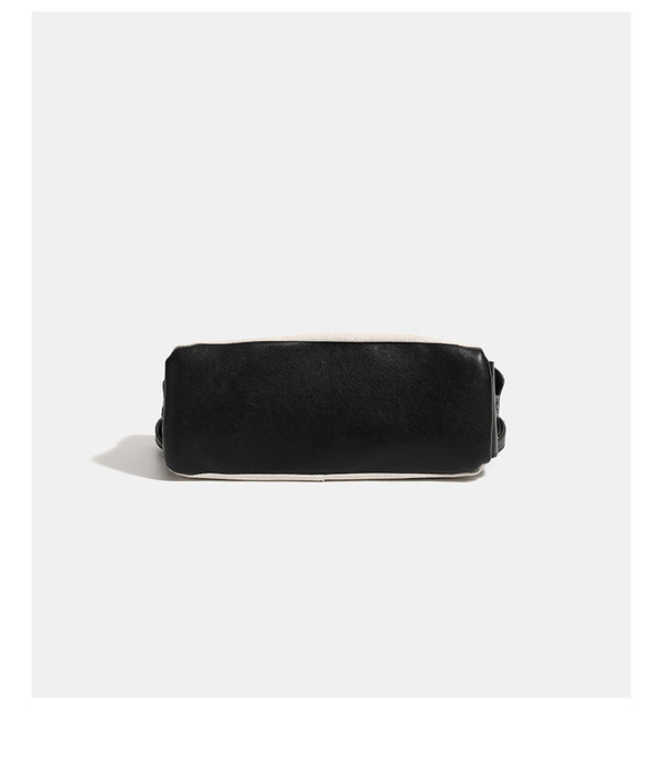 Off-white canvas shoulder bag with black leather-look trim, gold-tone ring hardware, top zip closure, side flap pocket, and